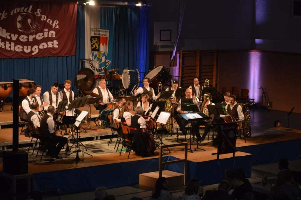 Im letzen Teil des Konzertes sitzen weniger Musikerinnen und Musiker auf der Bühne. Sie tragen die Vereinsweste und ein weißes Hemd des Musikvereins.