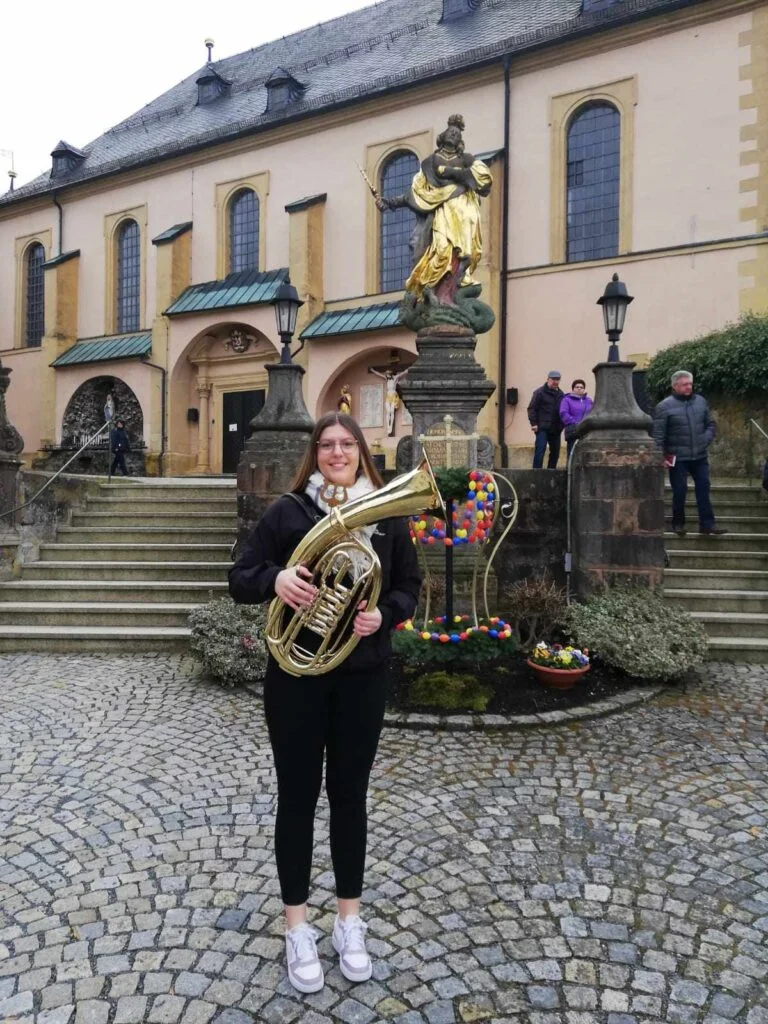 Die Musikerein mit Instrument steht vor der Basilika in Marienweiher